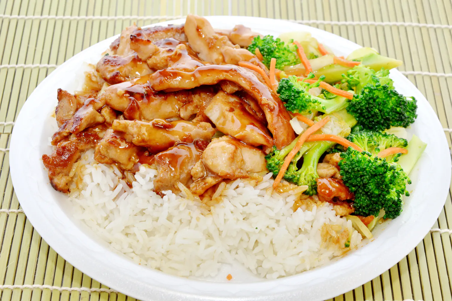 Teriyaki chicken served over steamed white rice with broccoli and shredded carrots
